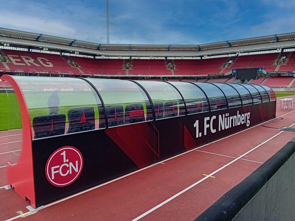 Folierte Spielerbank des 1. FC Nürnberg mit Vereinslogo und roter Bandenwerbung im Stadion