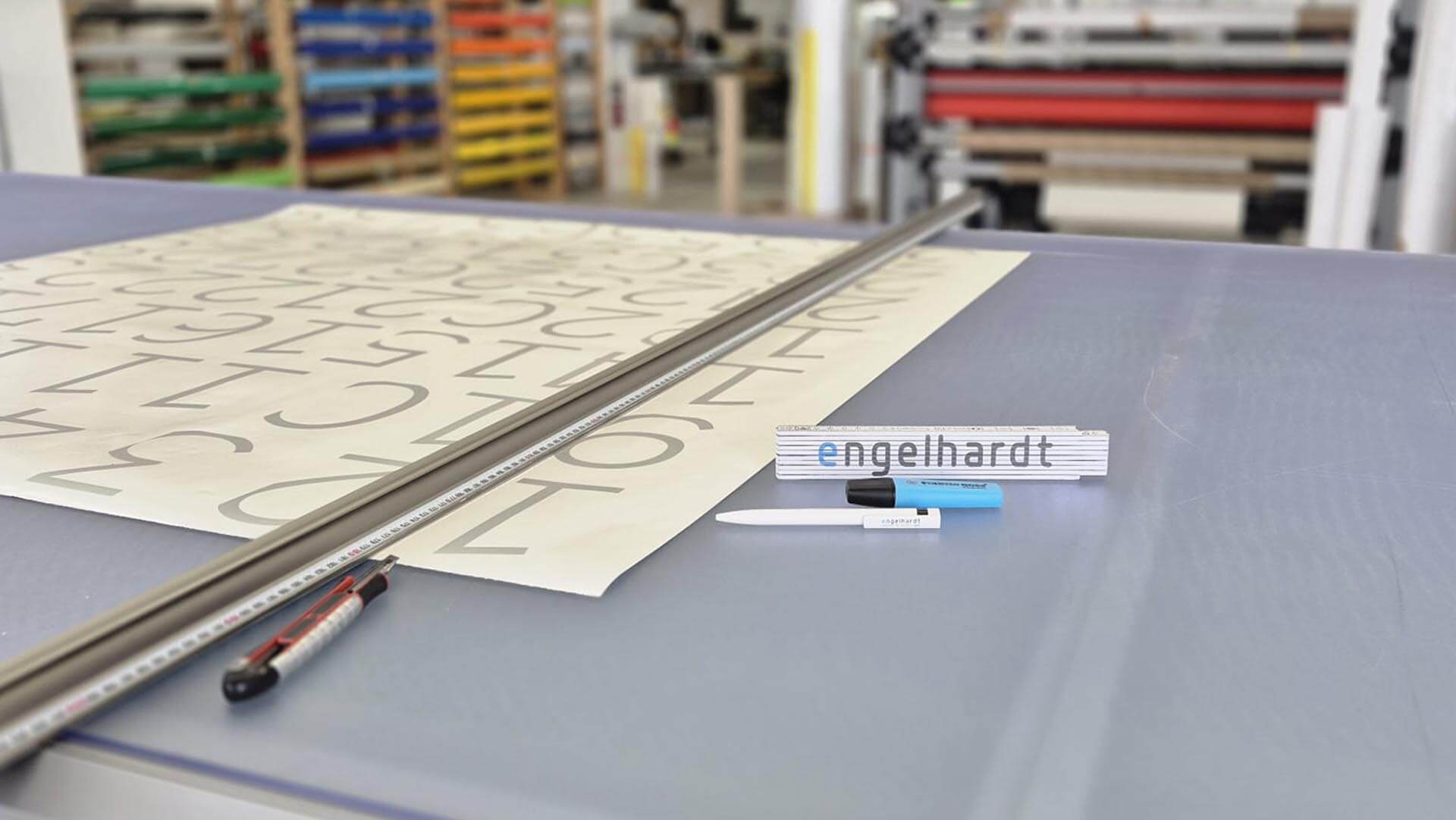 engelhardt-coburg-werbetechnik-print-produktion Werbetechnik-Produktion bei Engelhardt Coburg mit Schneidetisch, Folien und Produktionsmaschinen im Hintergrund