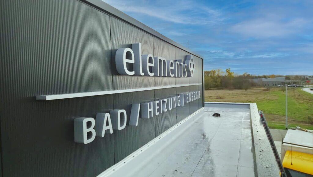 Beleuchtete elements-Dachwerbung für Bad, Heizung und Elektro an einem Gewerbegebäude