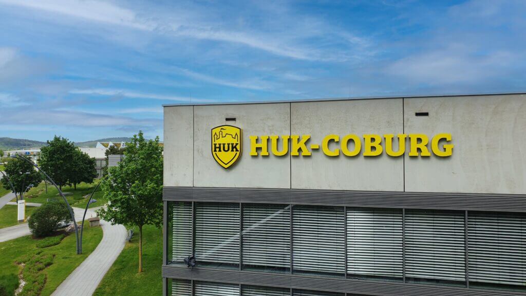 Gelbe HUK-COBURG-Fassadenbuchstaben am Postverteilzentrum vor blauem Himmel
