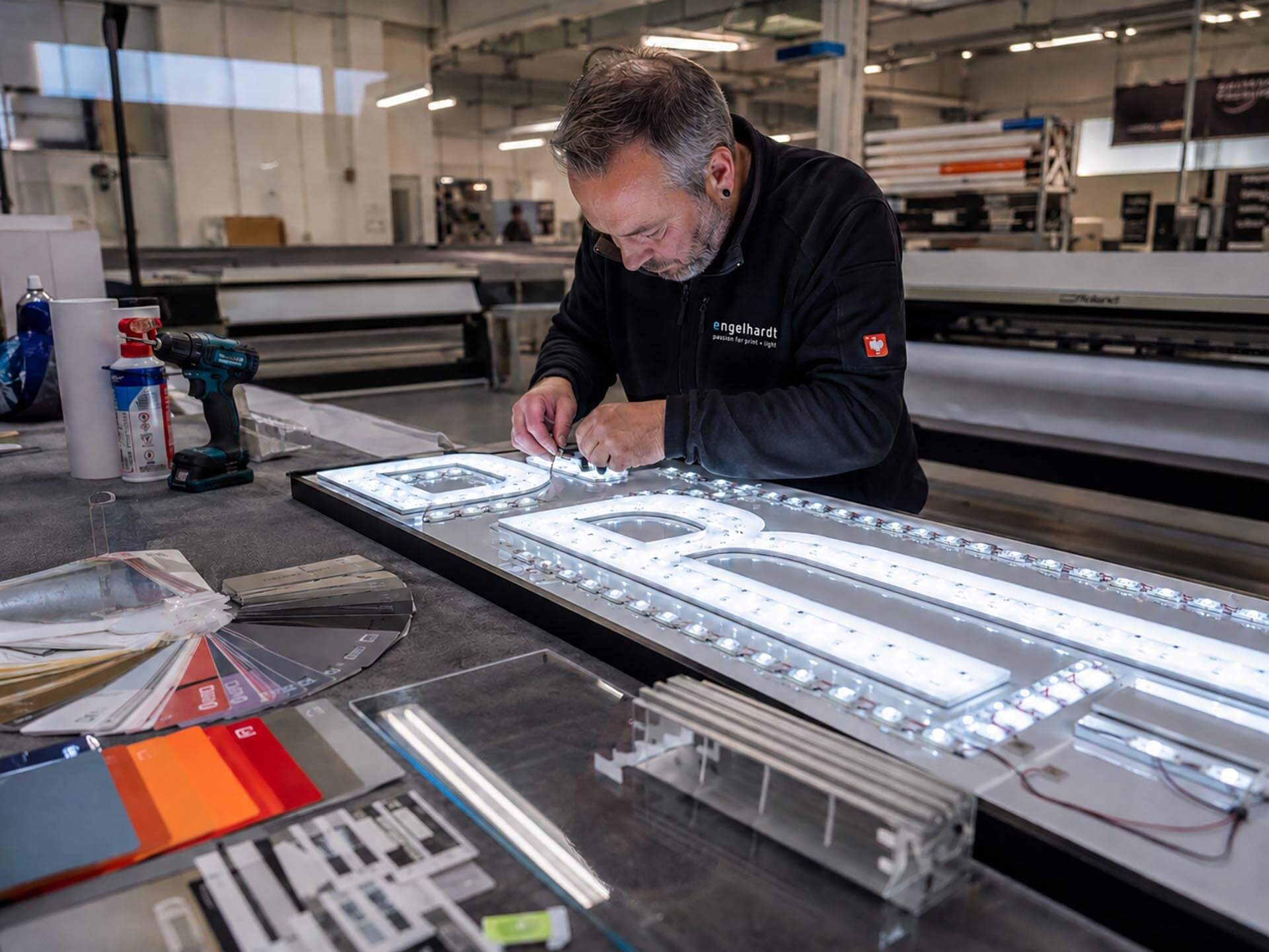 fertigung-mit-verstaendnis Fertigung von Lichtwerbung bei Engelhardt Coburg – Mitarbeiter montiert LED-Technik an einer beleuchteten Werbeanlage